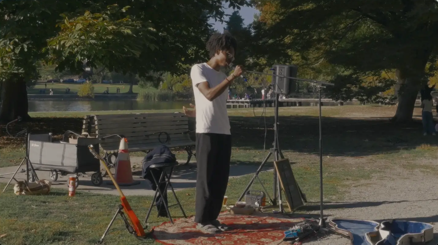 Still from the film: Ahrod performing with a microphone in a Seattle park